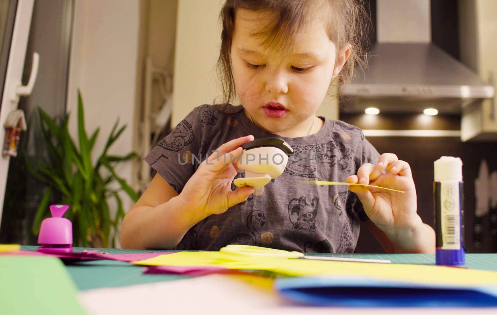Little girl cutting birds from yellow paper by Chudakov