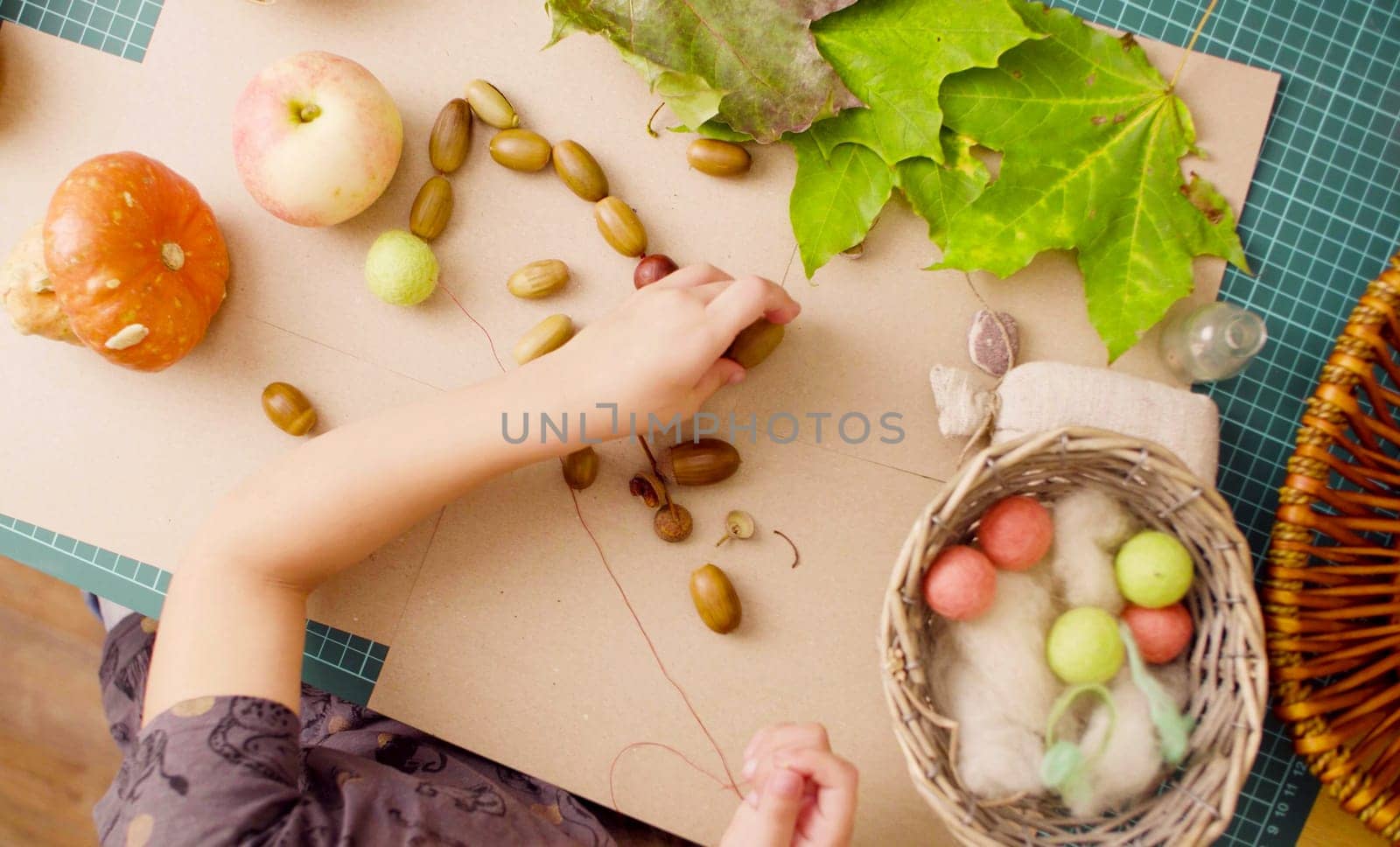 Little girl making necklace of acorns by Chudakov
