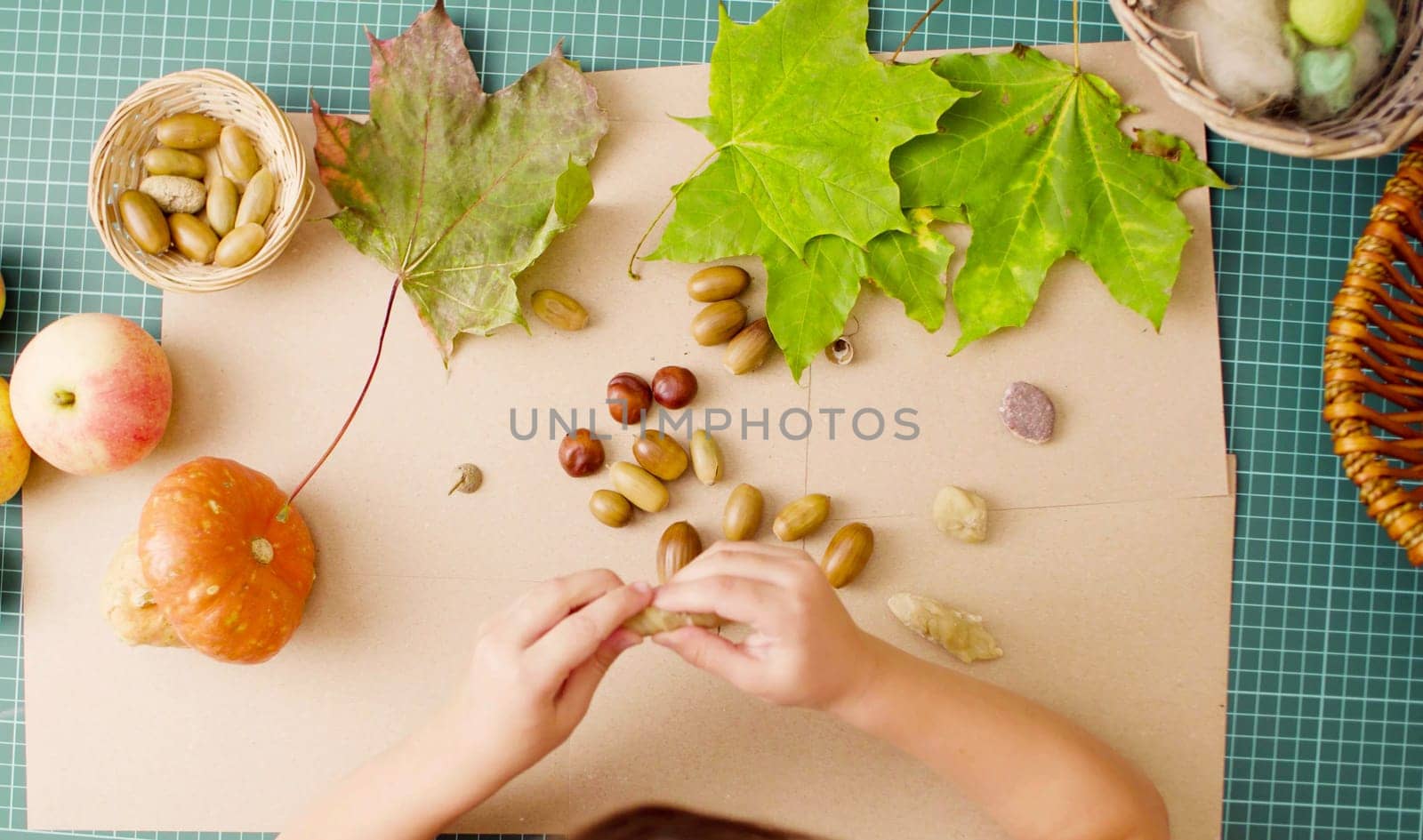 Little girl making necklace of acorns by Chudakov