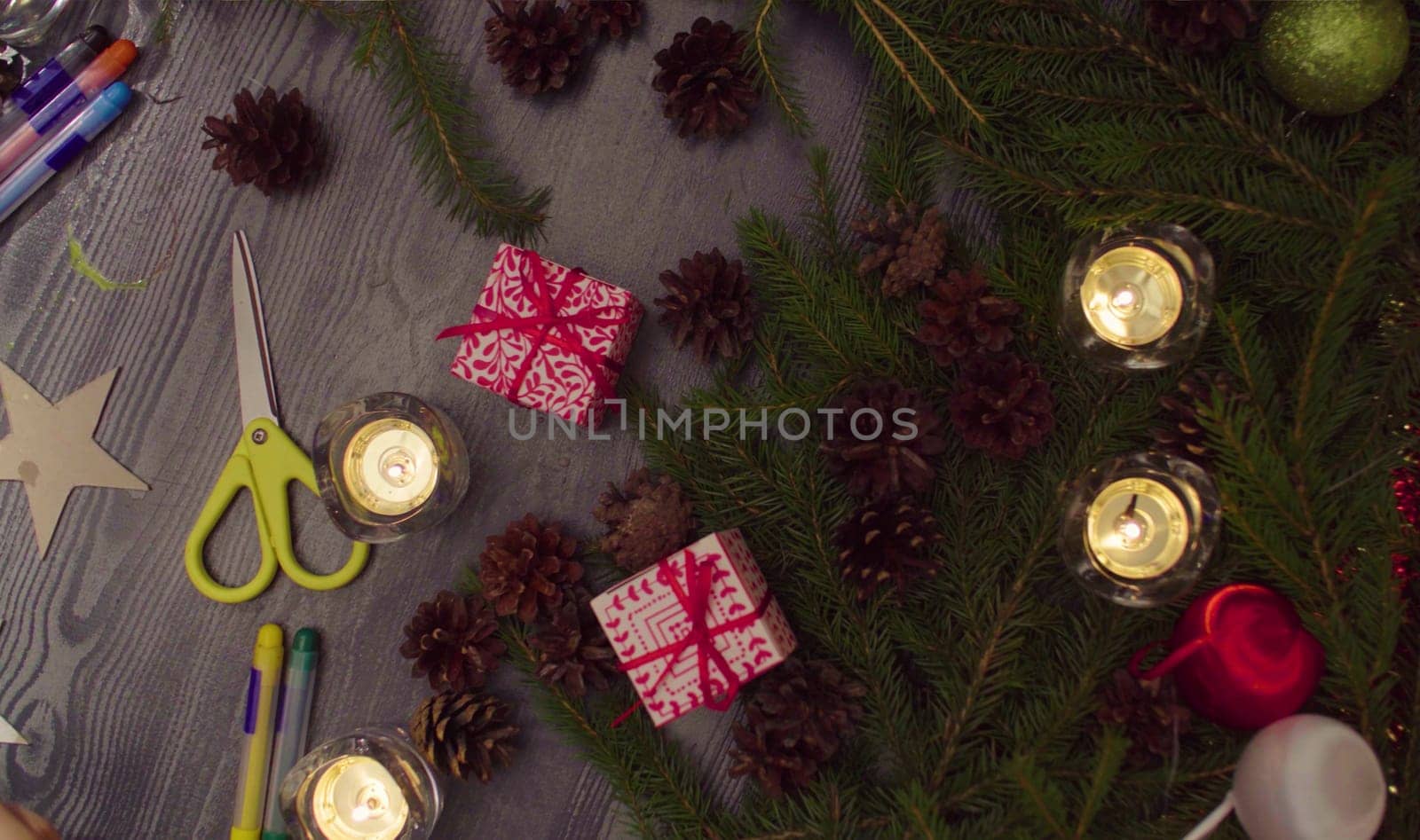 Top view Christmas gifts and burning candles in a dark room. Table with New Year decorations