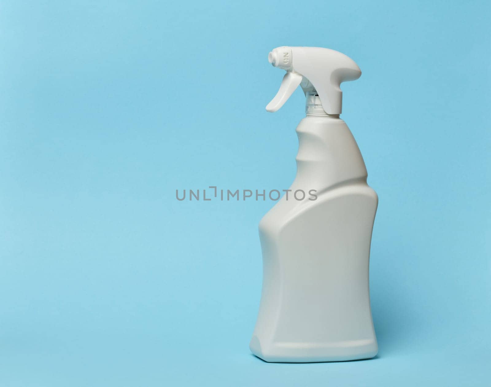 White plastic bottle with spray on a blue background, container for household chemicals by ndanko