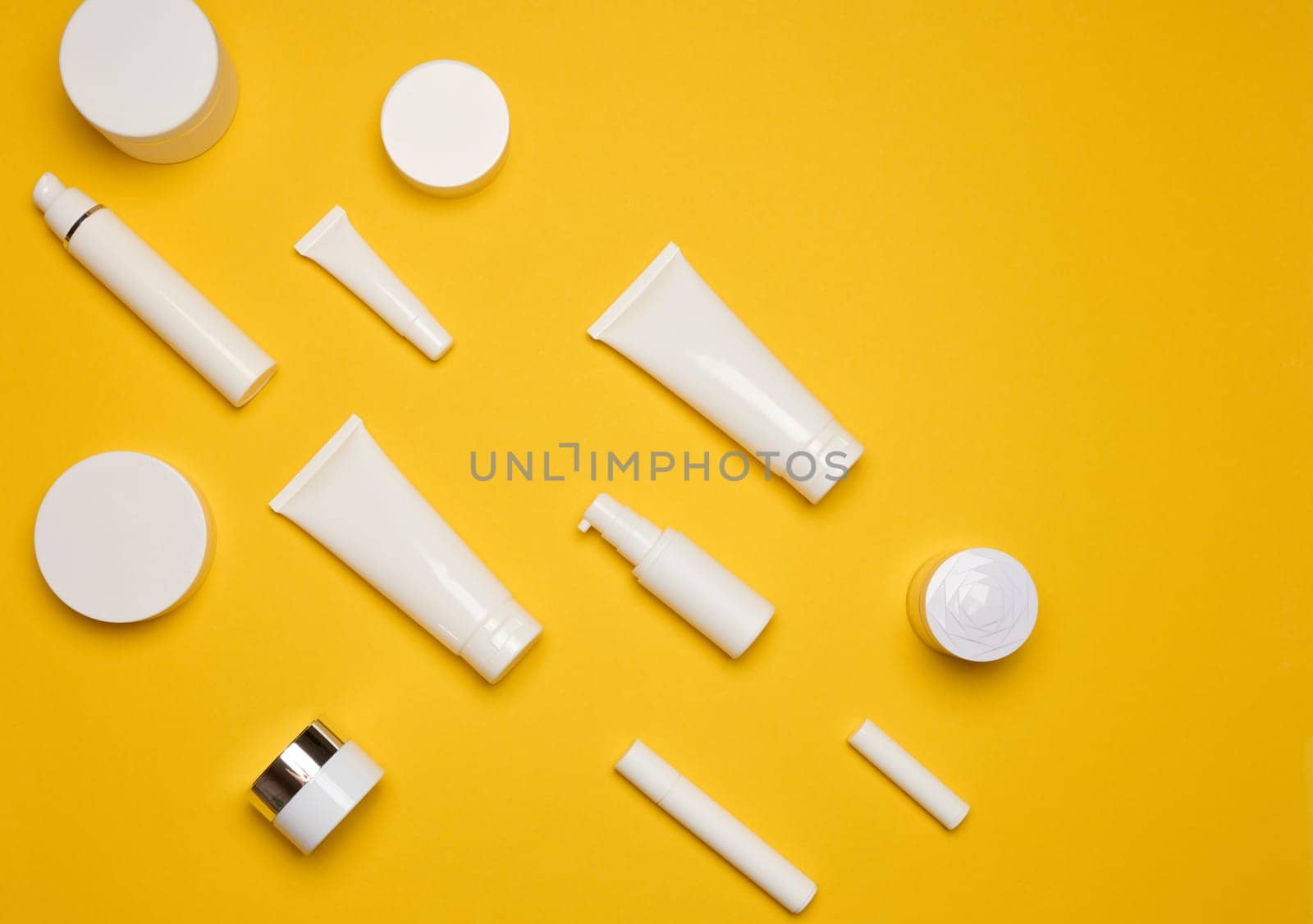 Various types of white plastic packaging, bottle, jar, tube on a yellow background. Container for cosmetics, top view