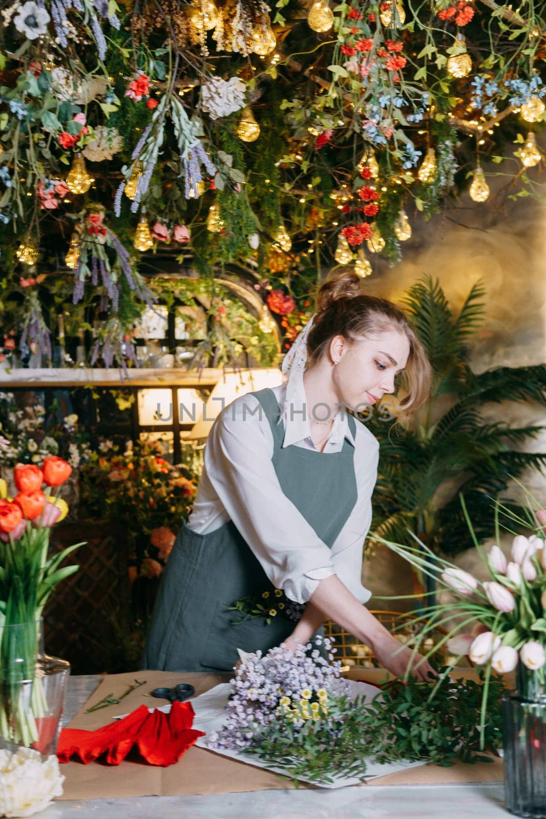 A woman in her florist shop collects bouquets of flowers. The concept of a small business. Bouquets of tulips for the holiday on March 8