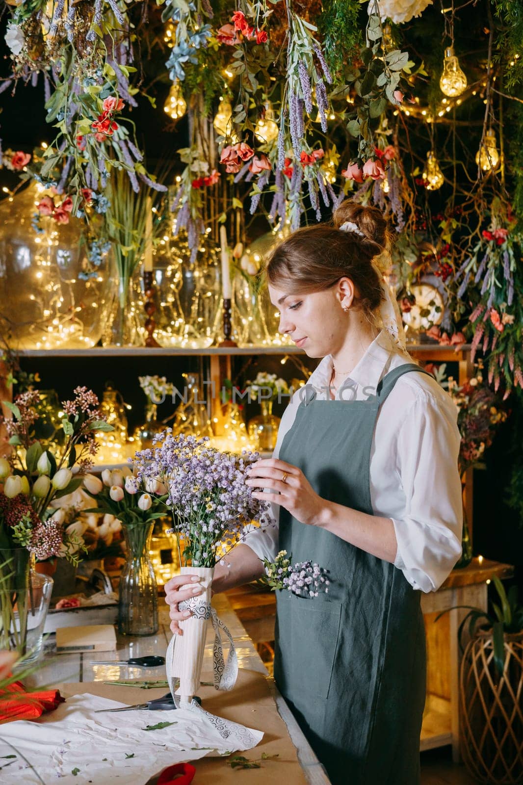 A woman in her florist shop collects bouquets of flowers. The concept of a small business. Bouquets of tulips for the holiday on March 8