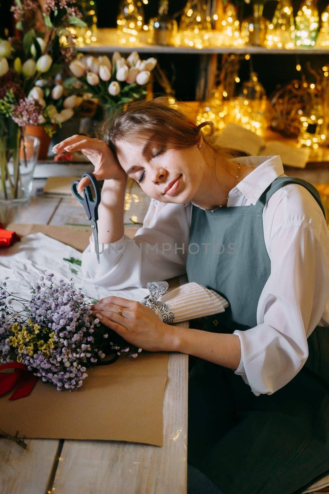 A woman in her florist shop collects bouquets of flowers. The concept of a small business. Bouquets of tulips for the holiday on March 8