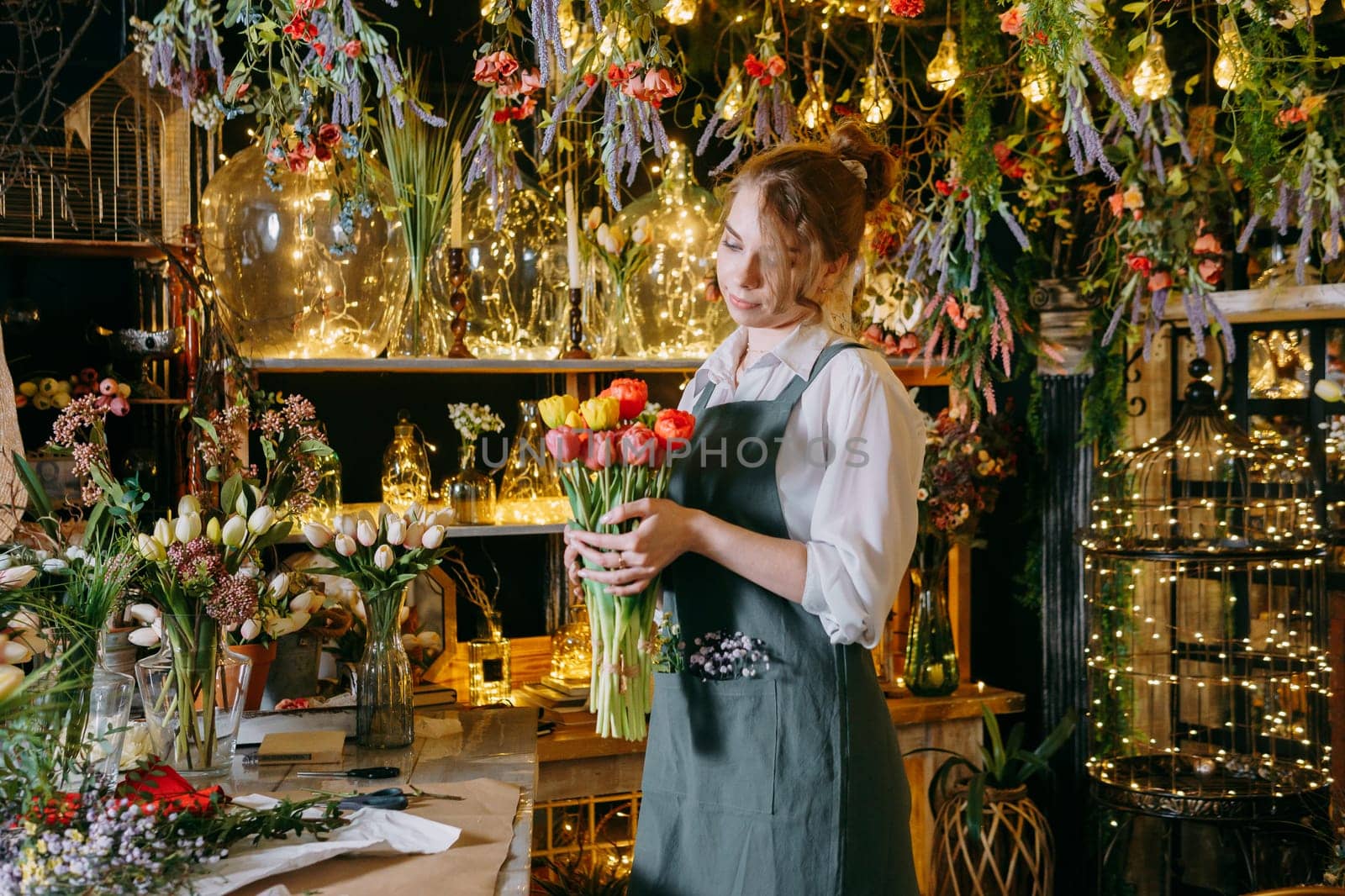 A woman in her florist shop collects bouquets of flowers. The concept of a small business. Bouquets of tulips for the holiday on March 8