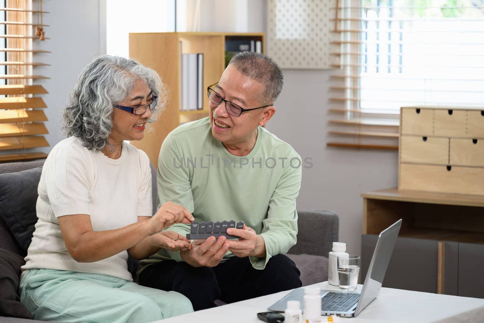 Middle aged couple sitting on couch while talking with experienced doctor online. Telehealth concept by prathanchorruangsak