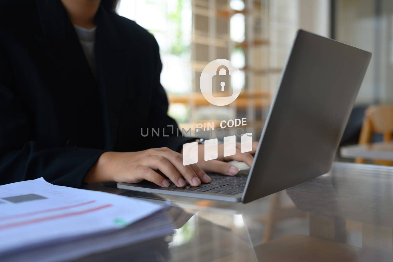 Businesswoman in black suit hands entering pin code on laptop. Cybersecurity concept by prathanchorruangsak