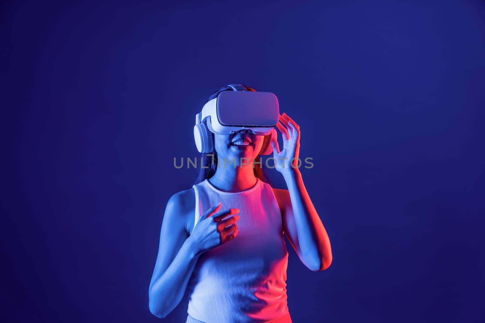 Smart female stand in cyberpunk neon light wearing VR headset connecting metaverse, futuristic cyberspace community technology. Elegant woman excited seeing generated virtual scenery. Hallucination.