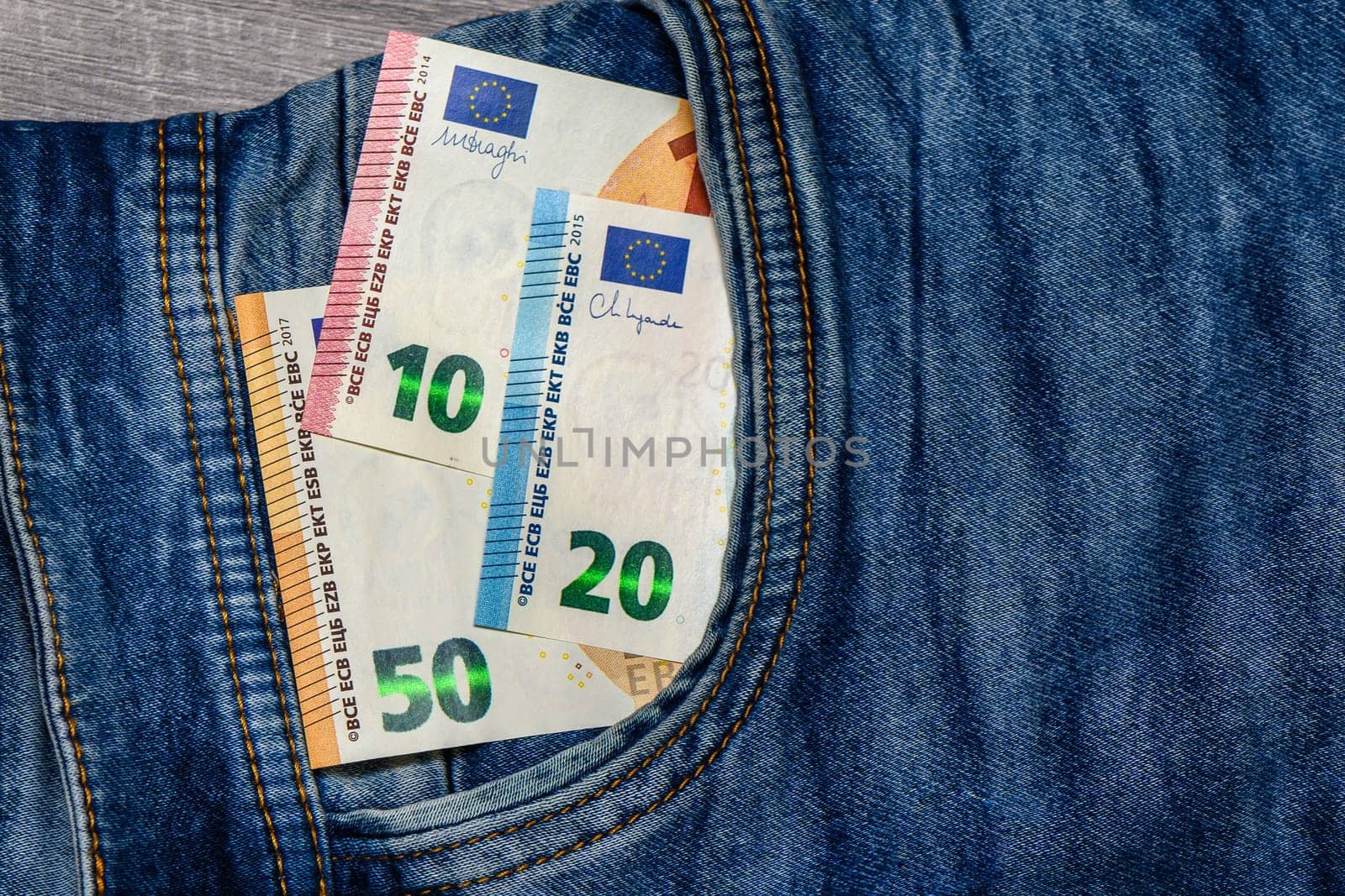 Three folded 50 Euro banknote bills stuck in front pocket of blue jeans by Mixa74