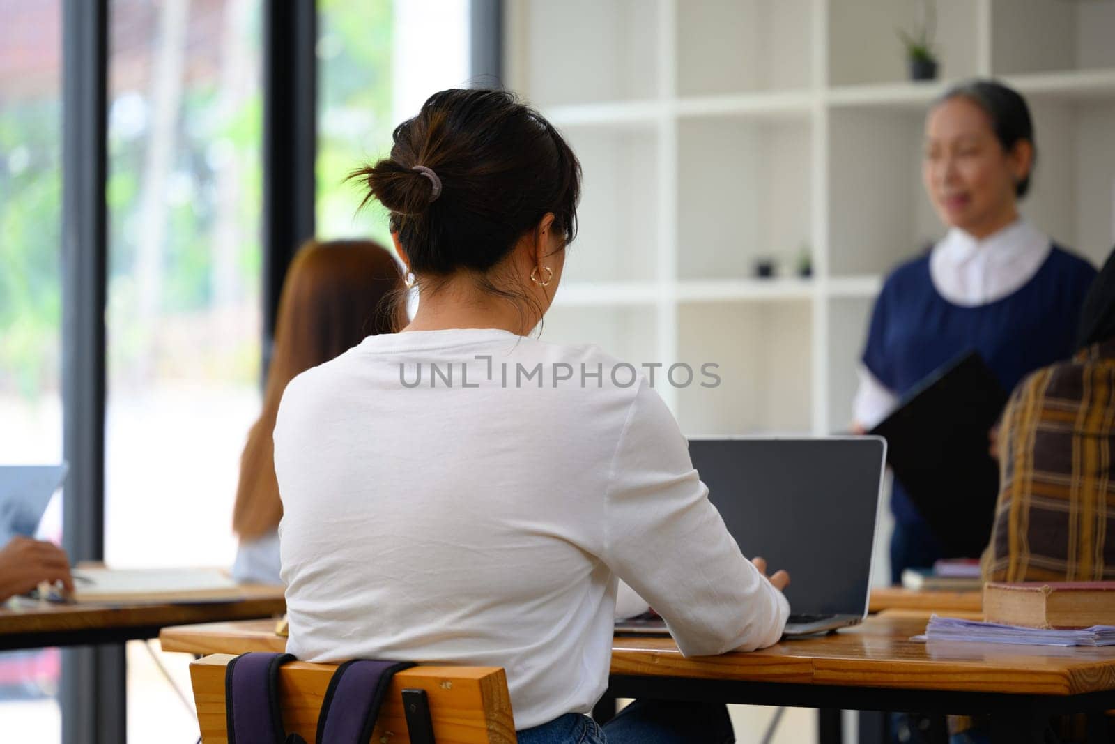 Back view of a female student using laptop during class at university.