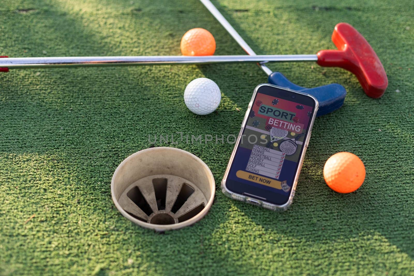 golf equipment on the green lawn. mini golf sports betting on a smartphone by Andelov13