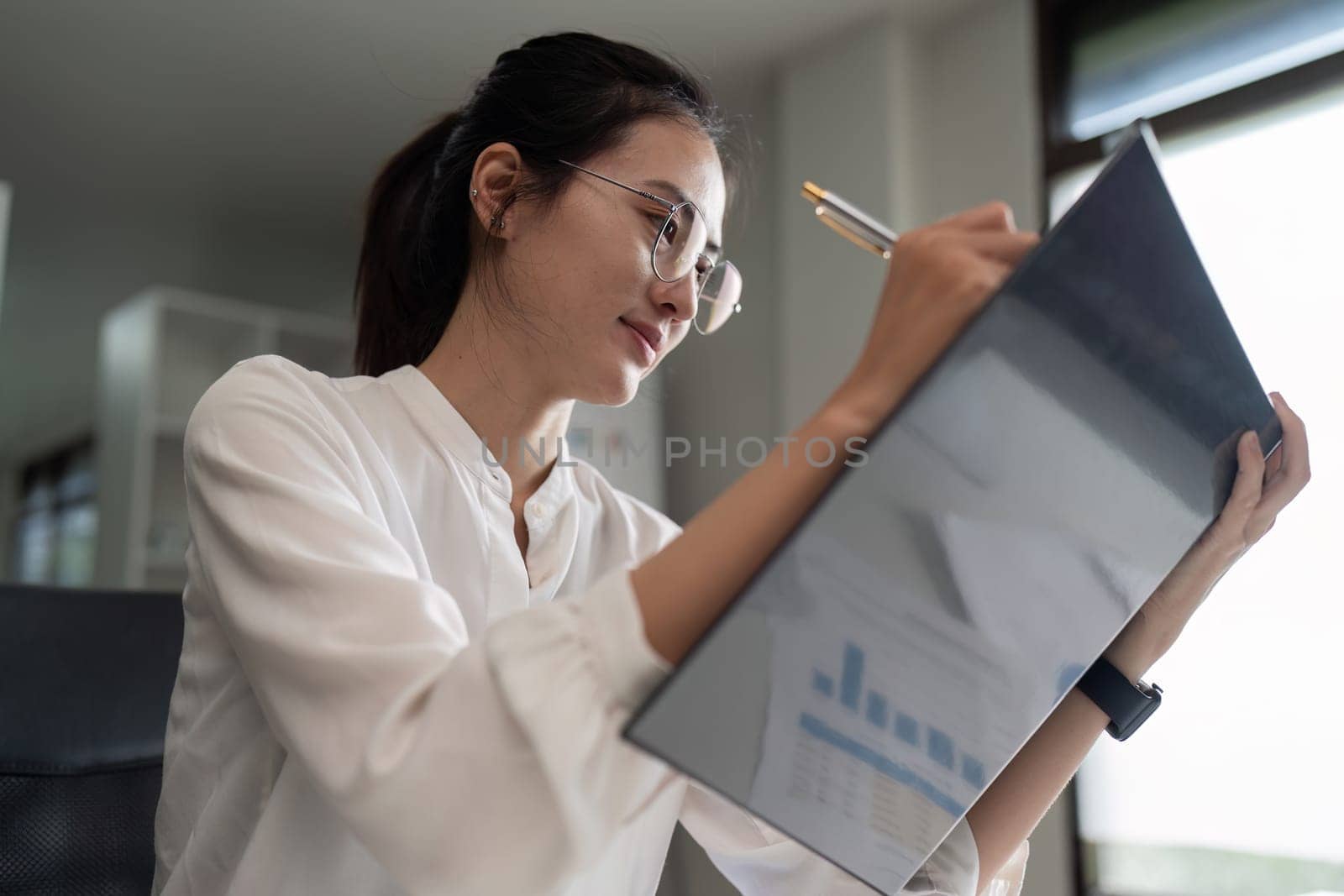 Portrait of an Asian woman working on a tablet computer in a modern office. Make an account analysis report.