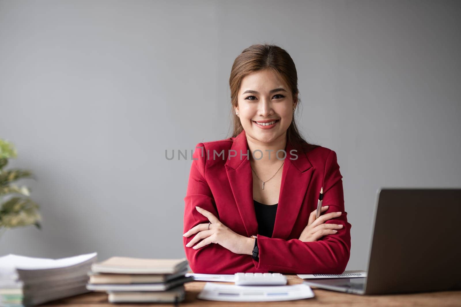 Portrait of a confident Asian business woman Working in a modern office desk using a laptop computer marketing concept by wichayada