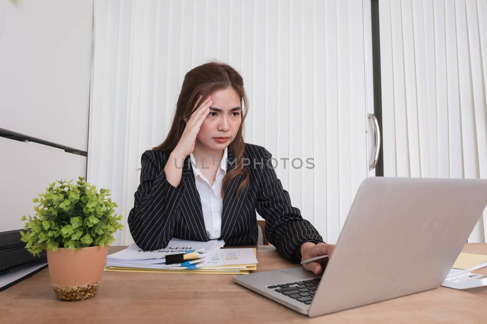 Young businesswoman has problems with her work in the office Feeling stressed and unhappy, showing a serious expression.