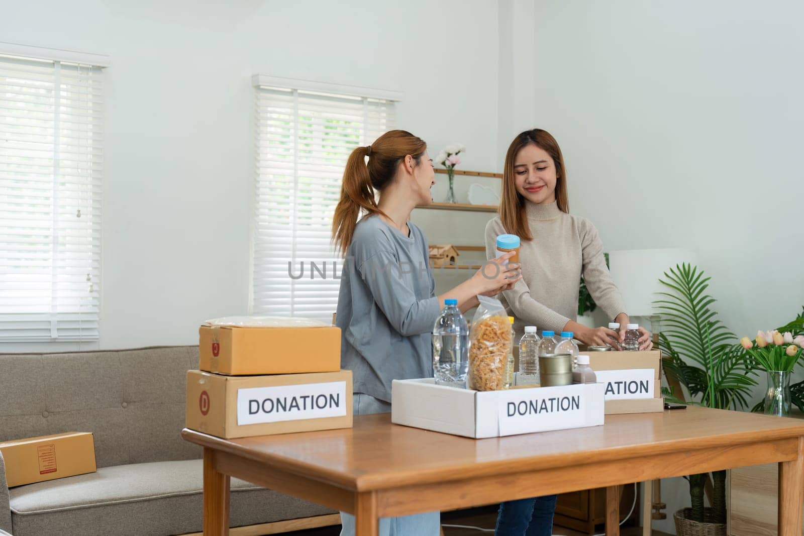 charity, donation and volunteering concept. Volunteer prepare foodstuff box containing food to donate to people poor, disaster victim at home.