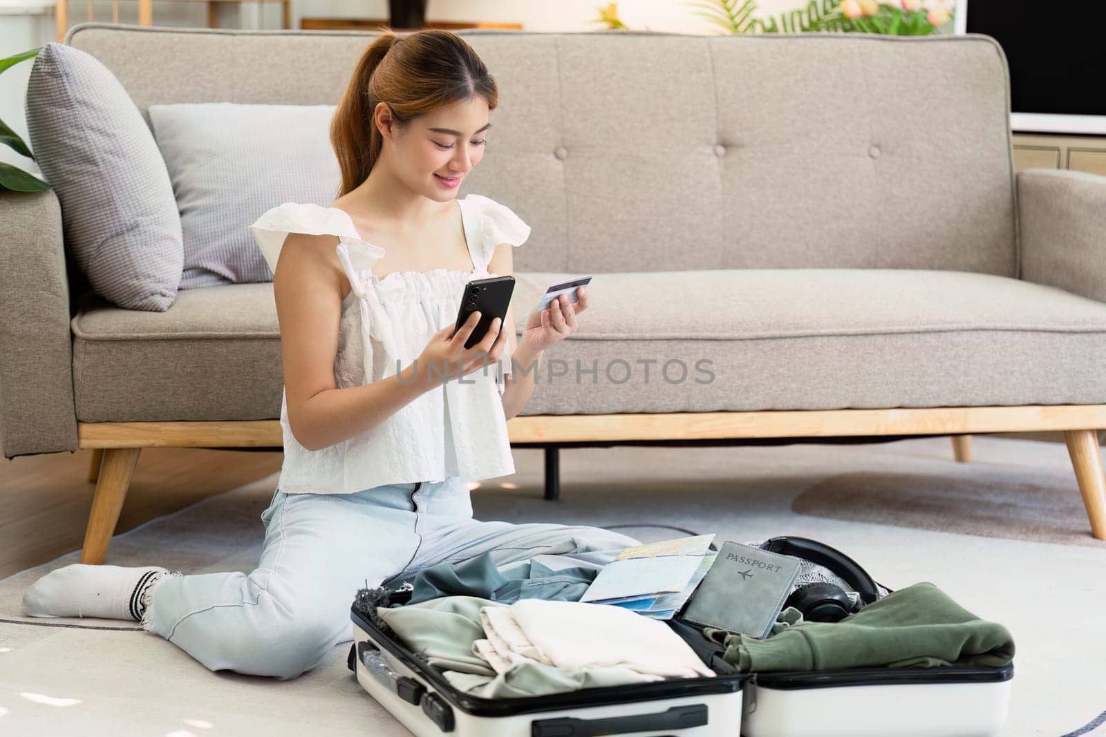 Happy young woman with credit card booking vacation at travel agency or making hotel reservation online by itchaznong