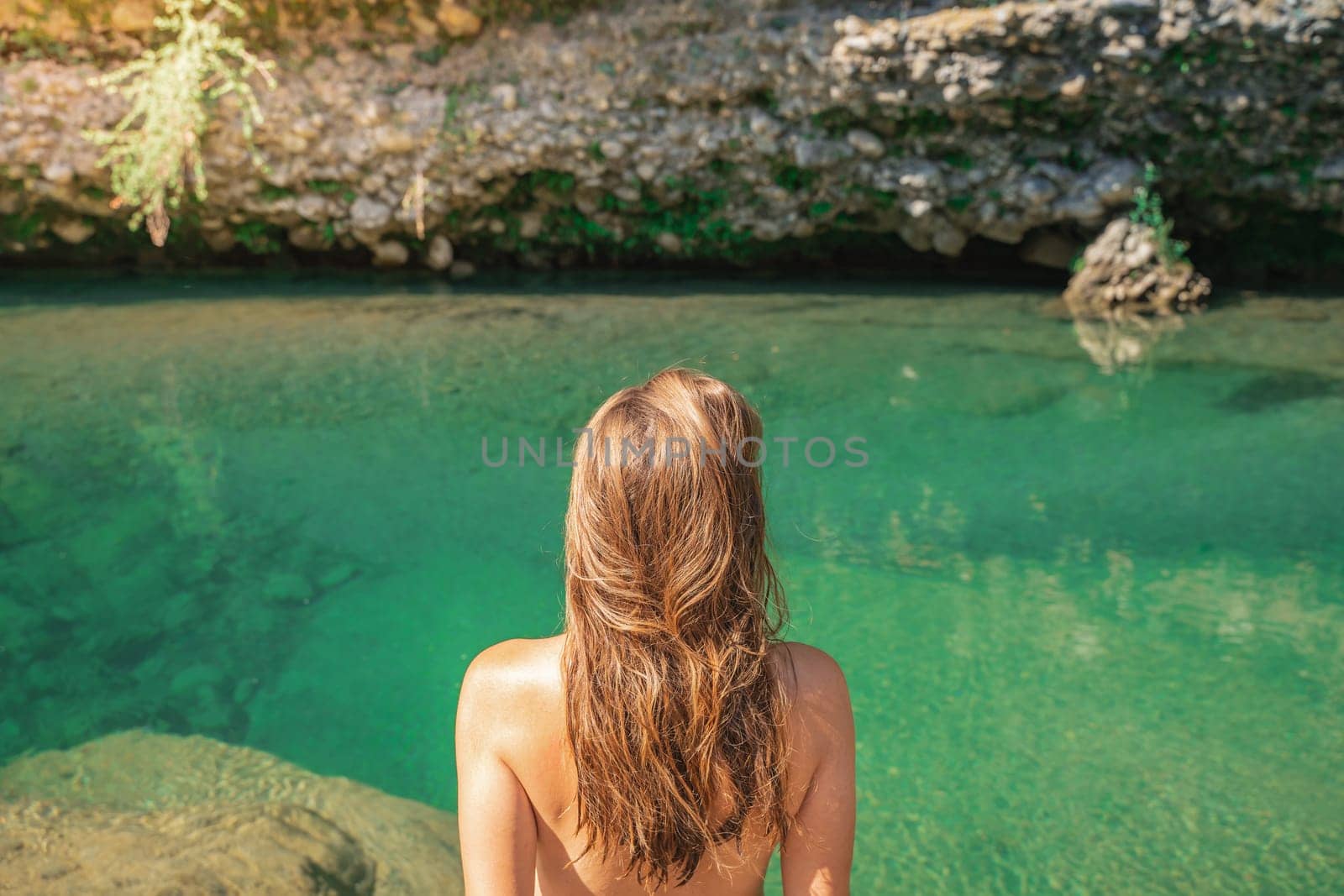 Summer background with a girl with golden blonde hair in front of a crystal clear river. High quality photo