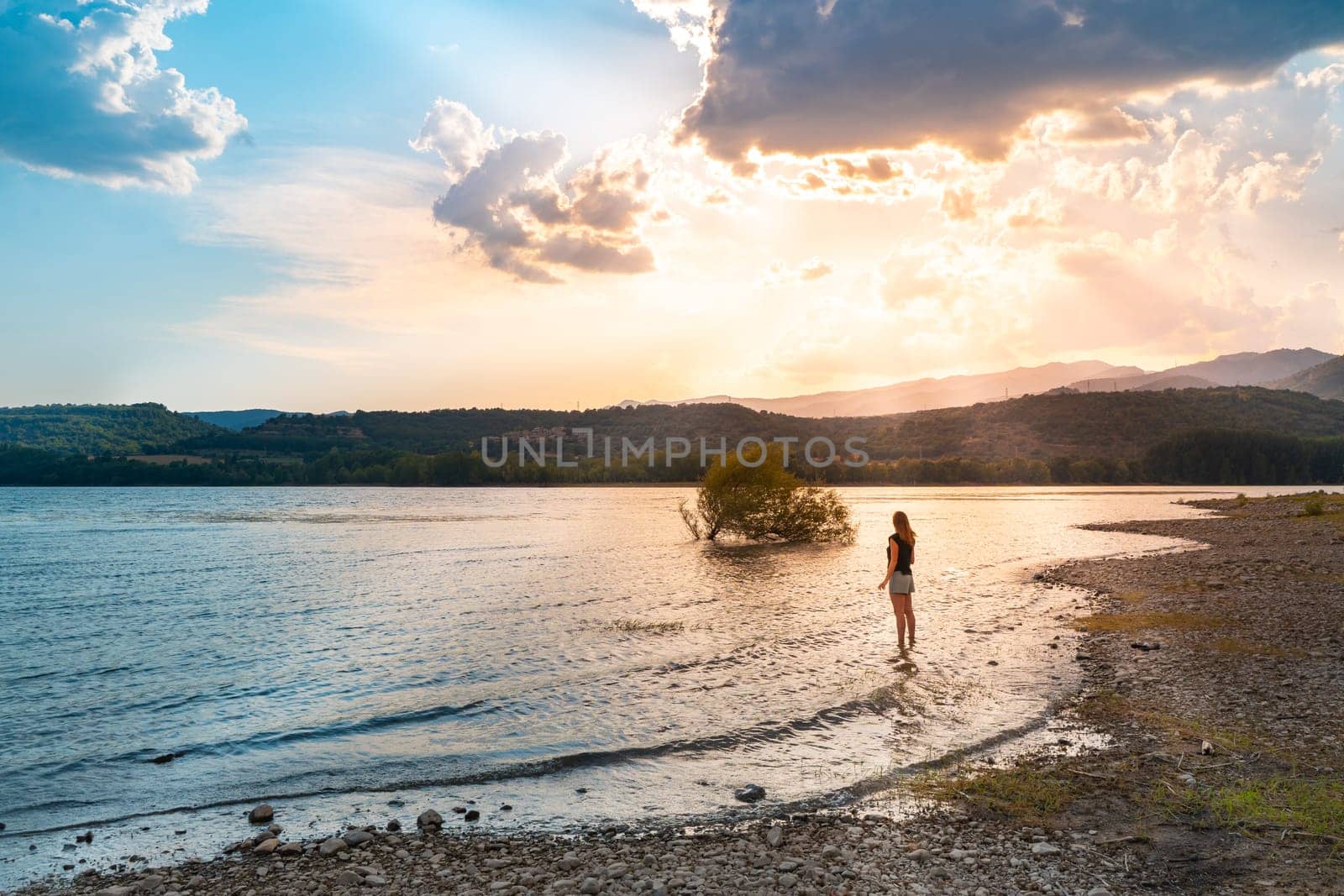 Woman silhouette in a majestic Lake with sun rays. Meditation Concept. High quality photo