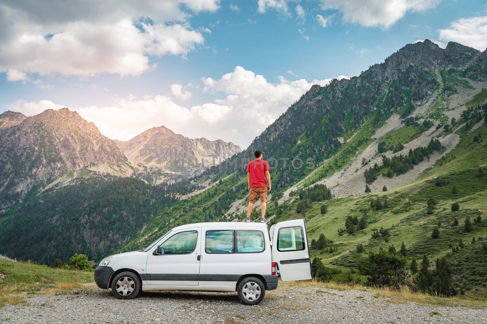 Young man enjoying nature on top of his camper van. High quality photo