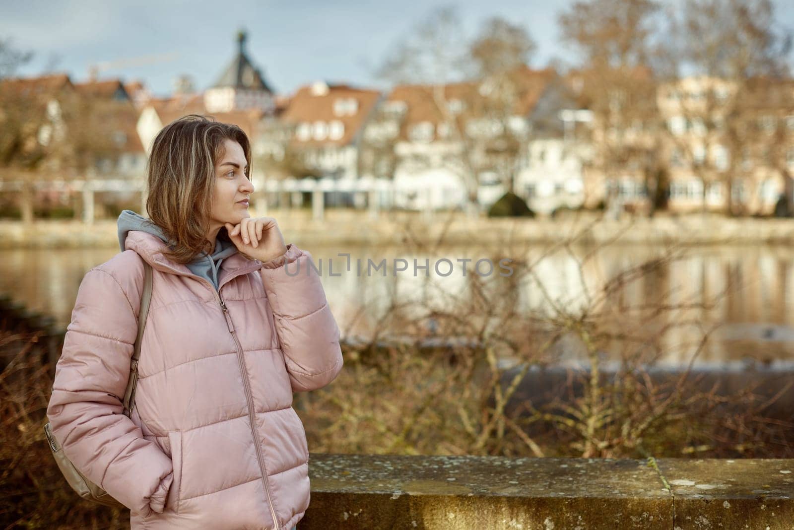 Young beautiful pretty tourist girl in warm hat and coat with backpack walking at cold autumn in Europe city enjoying her travel in Bietigheim-Bissingen, Deutschland. Outdoor portrait of young tourist woman enjoying sightseeing by Andrii_Ko