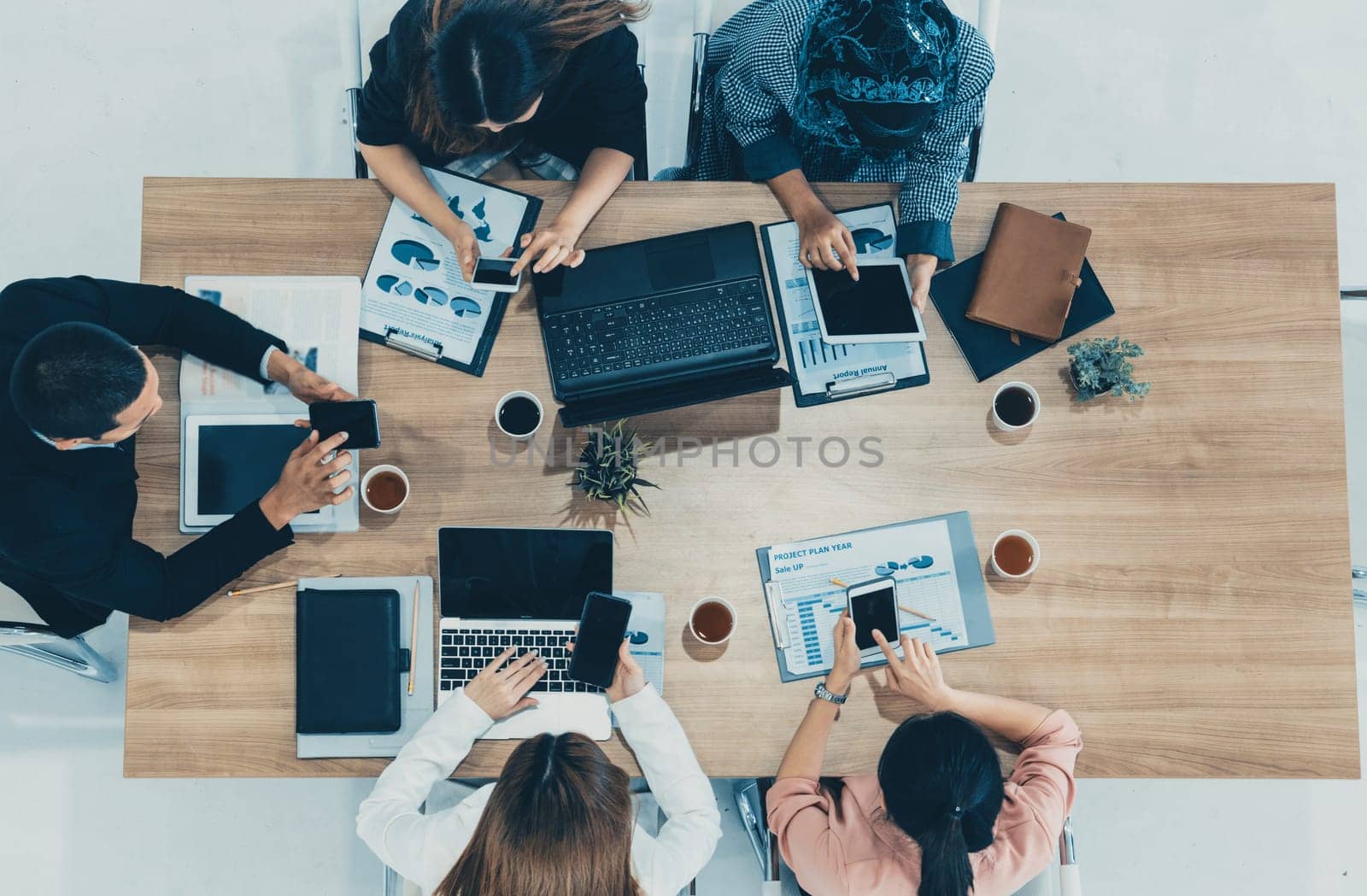 Top view of businessman executive in group meeting with other businessmen and businesswomen in modern office with laptop computer, coffee and document on table. People corporate business team uds