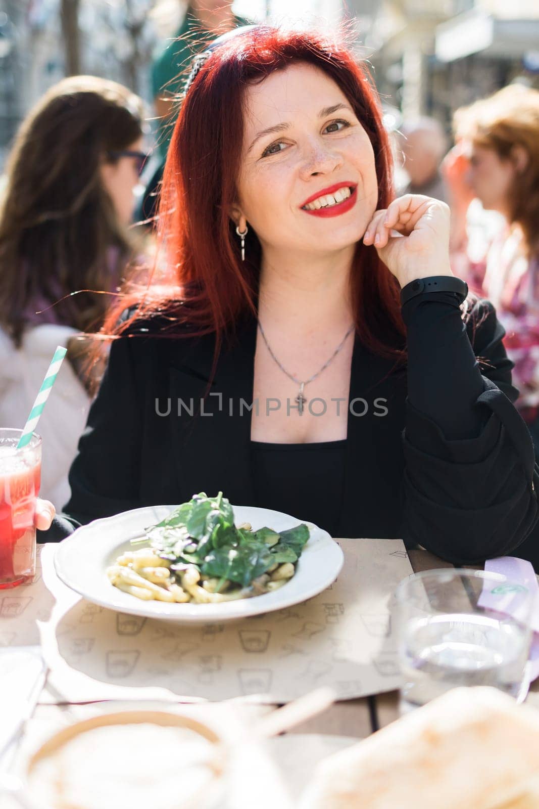 Millennial woman eating italian pasta at restaurant on the street in spring. Concept of Italian gastronomy and travel. Stylish woman with red hair by Satura86