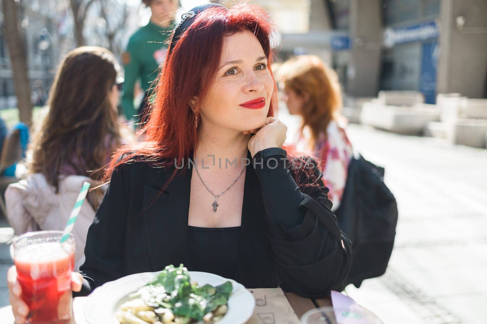 Millennial woman eating italian pasta at restaurant on the street in spring. Concept of Italian gastronomy and travel. Stylish woman with red hair by Satura86