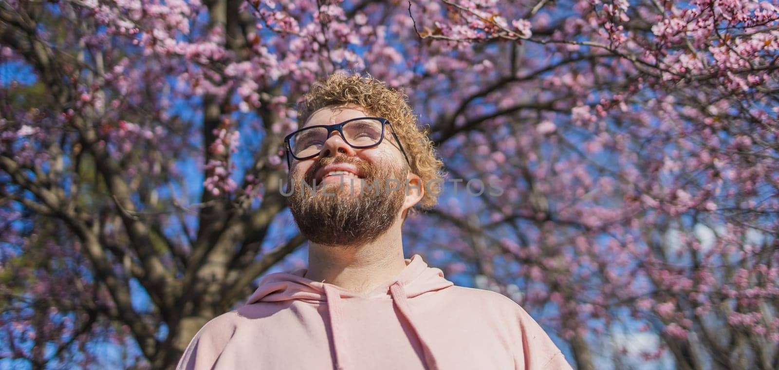 Banner Man allergic enjoying after treatment from seasonal allergy at spring. Portrait of happy bearded man smiling in front of blossom tree at springtime. Spring blooming and allergy concept. Copy space by Satura86