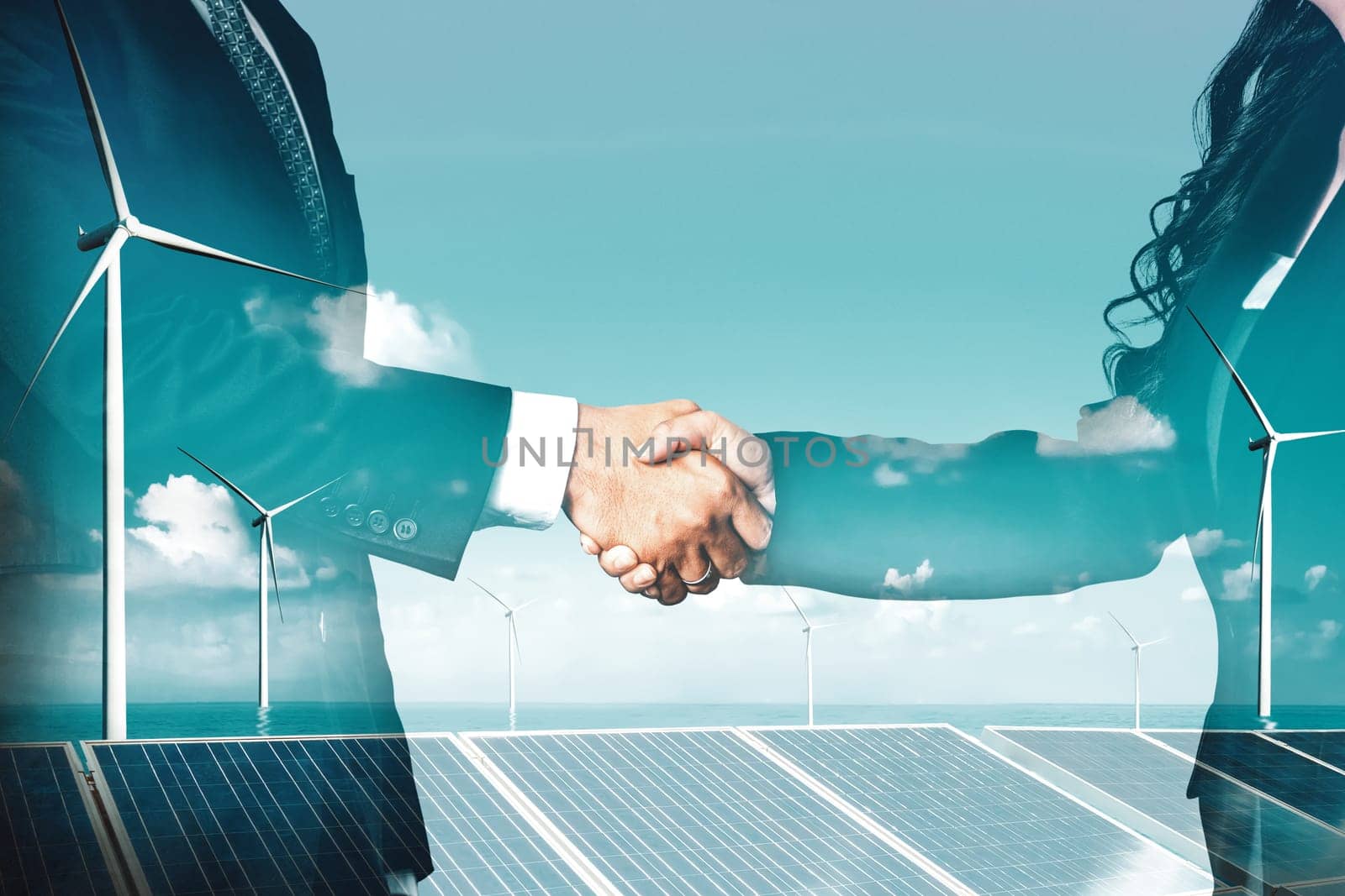Double exposure graphic of business people handshake over wind turbine farm and green renewable energy worker interface. Concept of sustainability development by alternative energy. uds