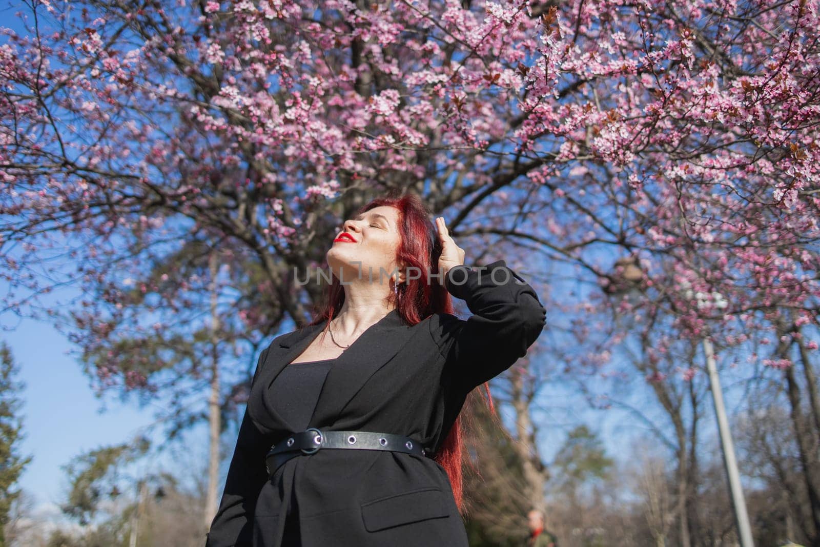 Woman with cherry flowers surrounded by blossoming trees copy space. Beauty and seasonal change and spring bloom season concept