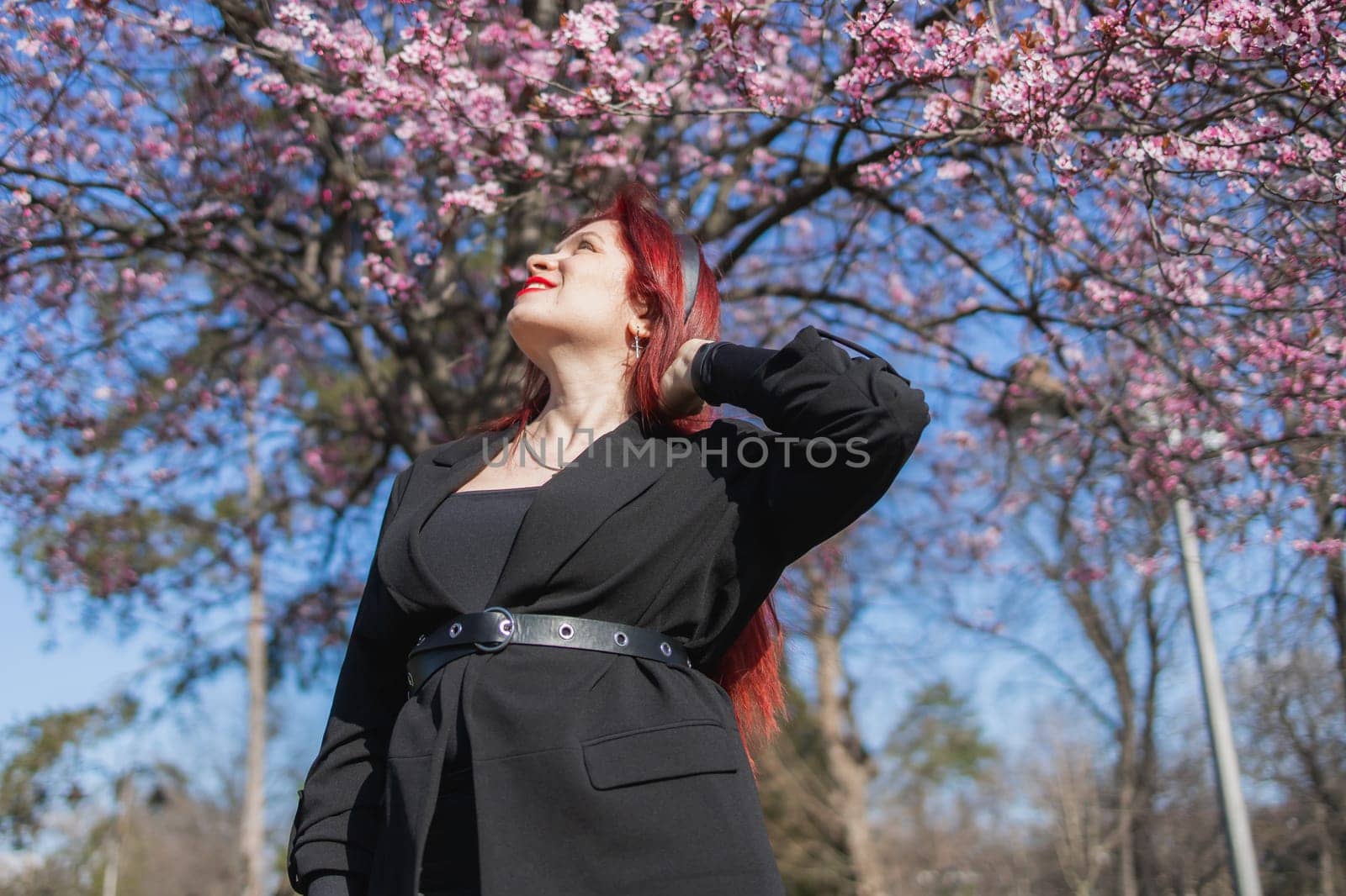 Woman with cherry flowers surrounded by blossoming trees copy space. Beauty and seasonal change and spring bloom season concept. by Satura86