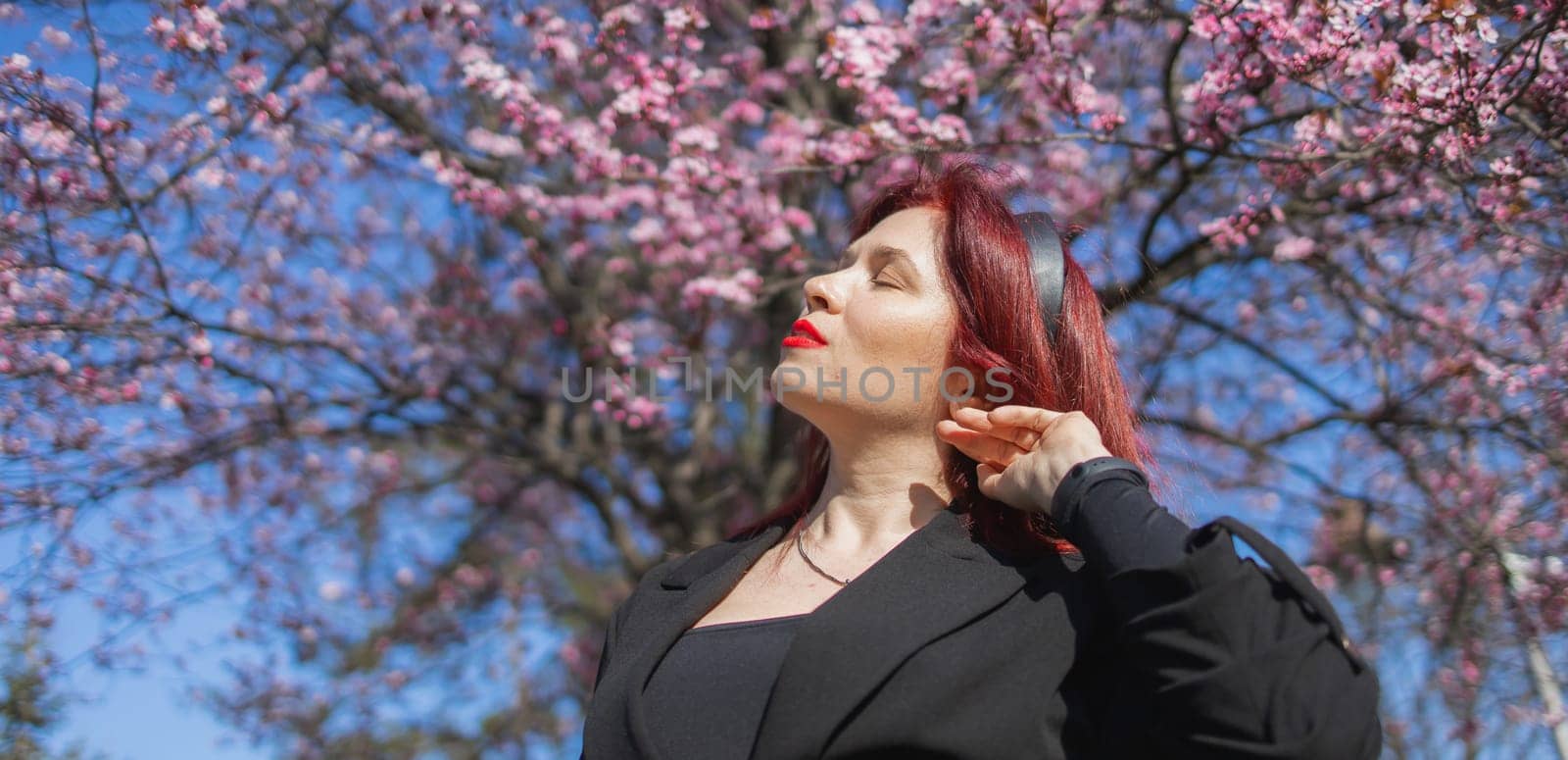 Banner Woman with cherry flowers surrounded by blossoming trees copy space. Beauty and seasonal change and spring bloom season concept. by Satura86