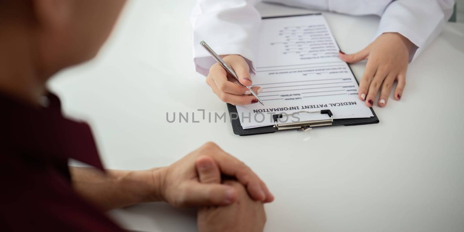 Doctor consulting male elderly patient filling medical form. Professional physician writing information in clipboard checking examining elderly man during appointment visit in clinic by nateemee