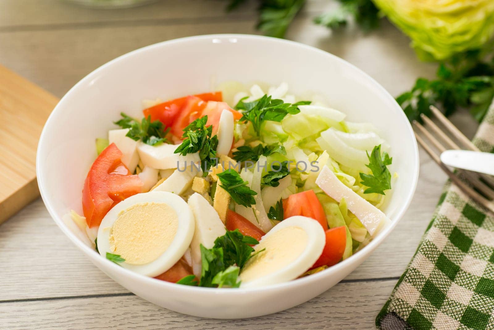 fresh vegetable salad, cabbage, tomatoes in a bowl on a wooden table .