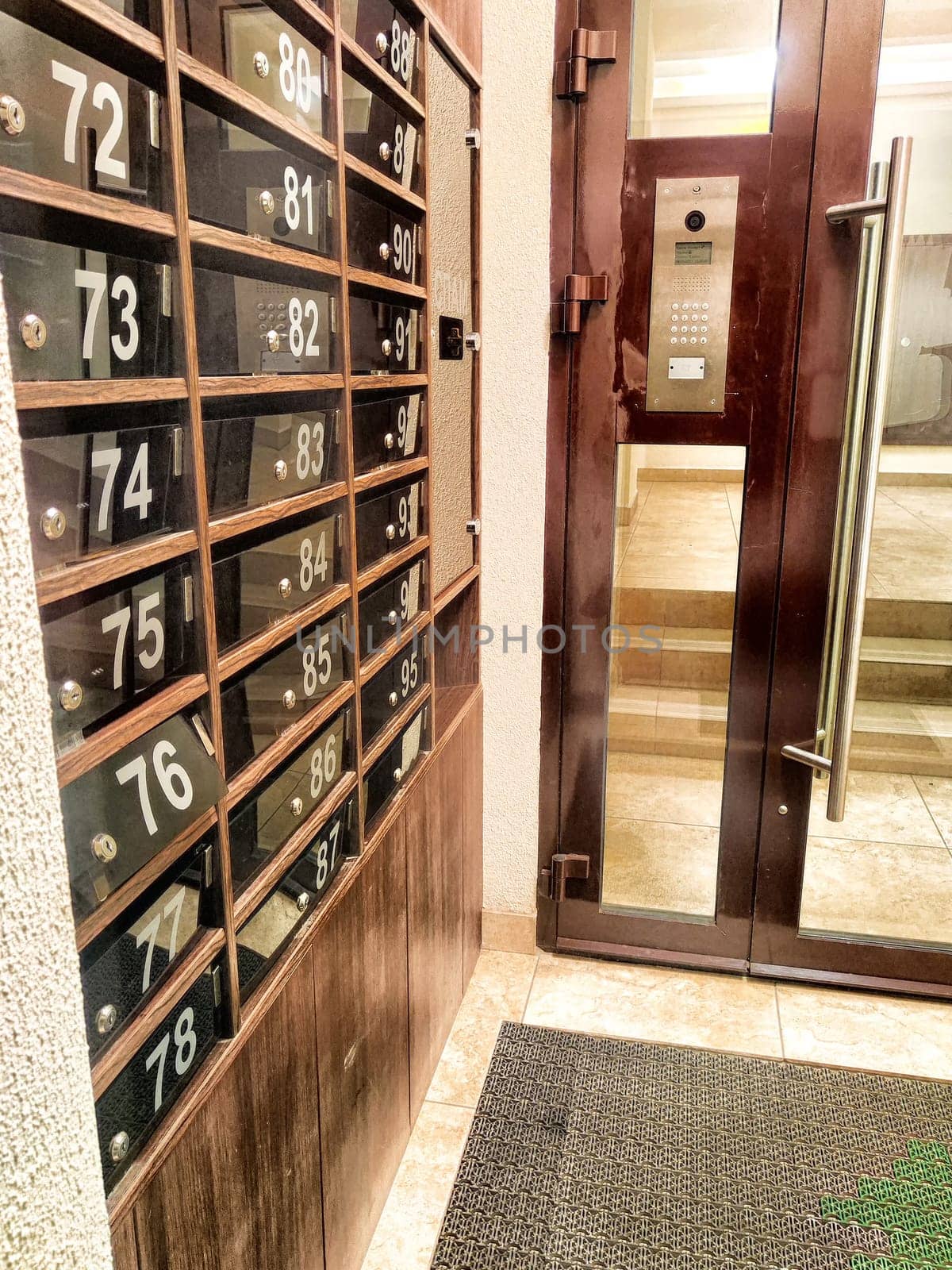 Mailboxes in hallway or entrance. Hallway featuring numbered mailboxes next to glass doors. Residential Building Entrance With Modern Mailboxes