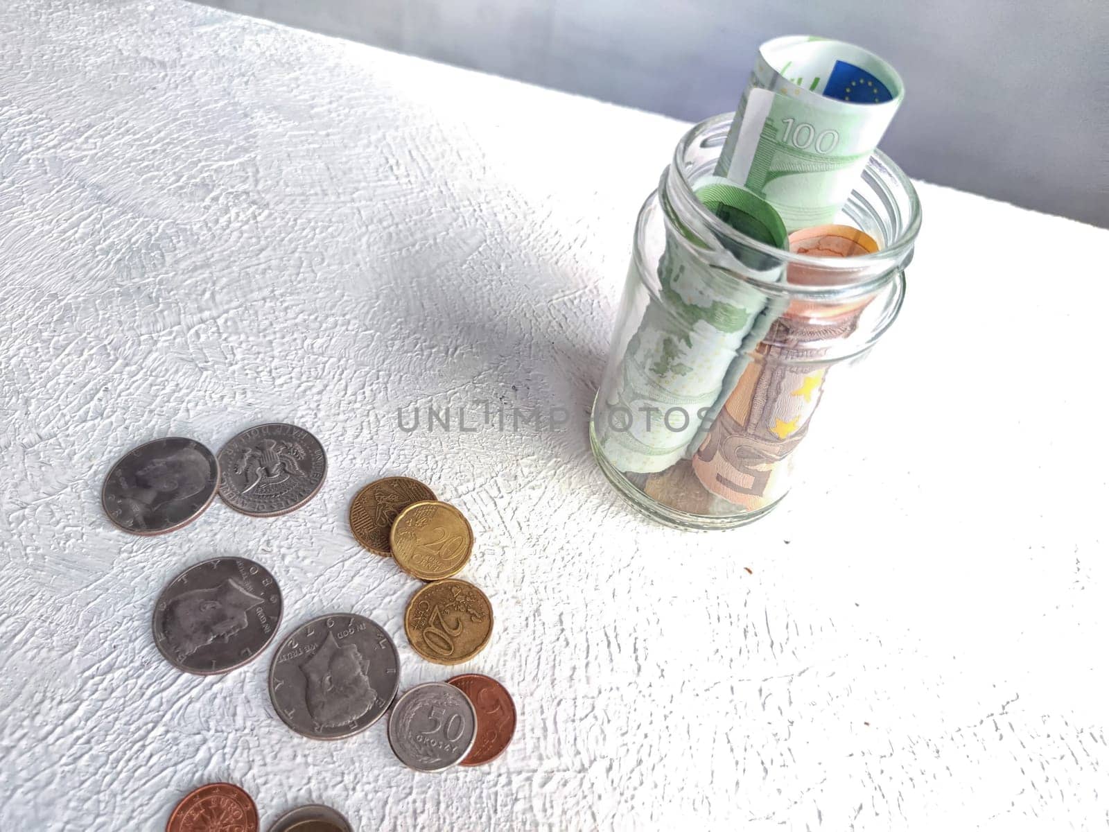 Glass Jar Filled With Euro Banknotes and Coins on Table. Concept of savings ranging from small money to large by keleny