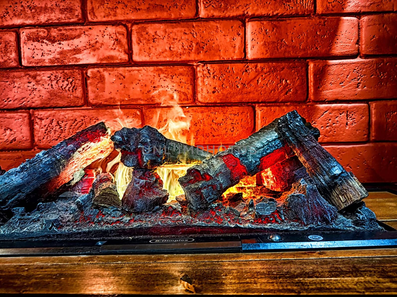 Fireplace. Firebrands, fire and a brick wall on the background. Firebrands ablaze with a cozy flame against a brick backdrop