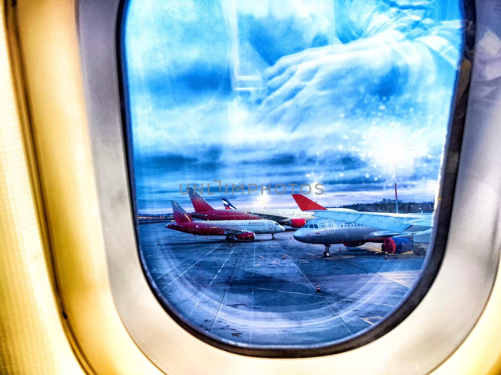 Moscow, Russia - April, 2024: View of the planes at the airport. Airplanes on Tarmac Seen Through Airplane Window at Dusk. Airplanes lined up on