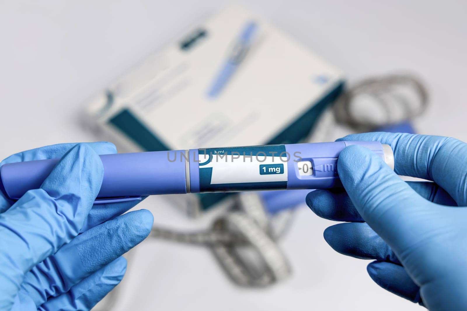 Hands in blue surgical gloves holding Ozempic Insulin injection pen for diabetics.
