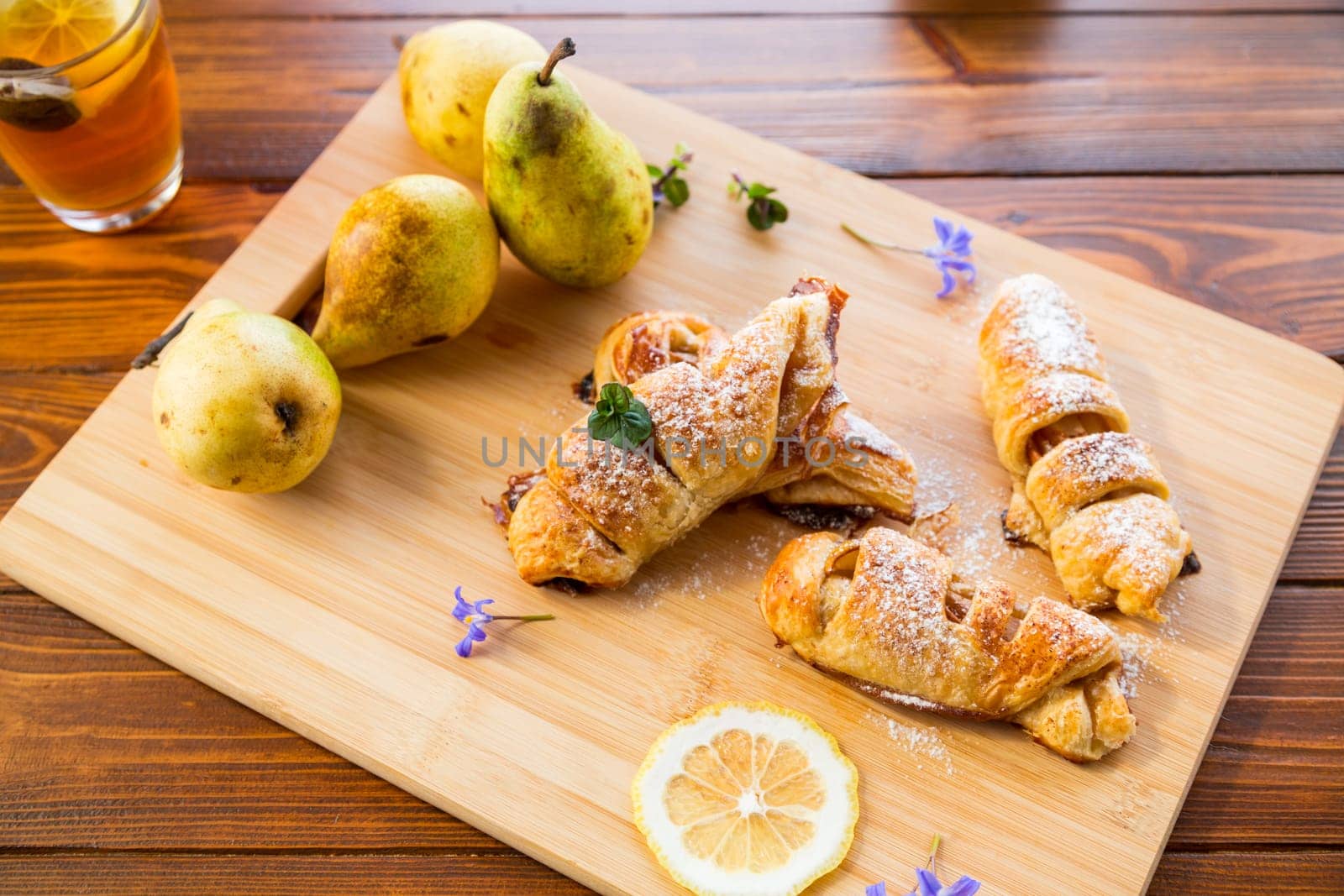 Sweet pastries, puff pastries with pears, on a wooden table by Rawlik
