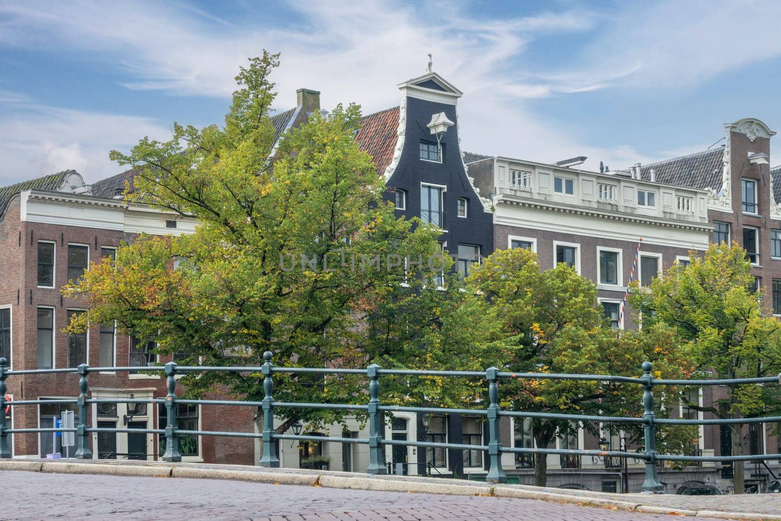 Netherlands. A day in Amsterdam. Facades of typical buildings on the canal embankment. High clouds in the blue sky