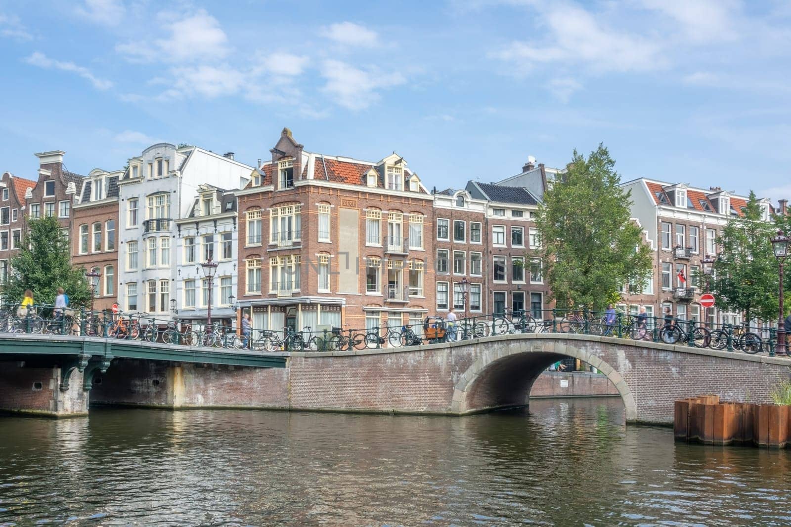 Netherlands. Summer day. Typical Dutch houses on the waterfront of Amsterdam. Stone bridges at the confluence of canals