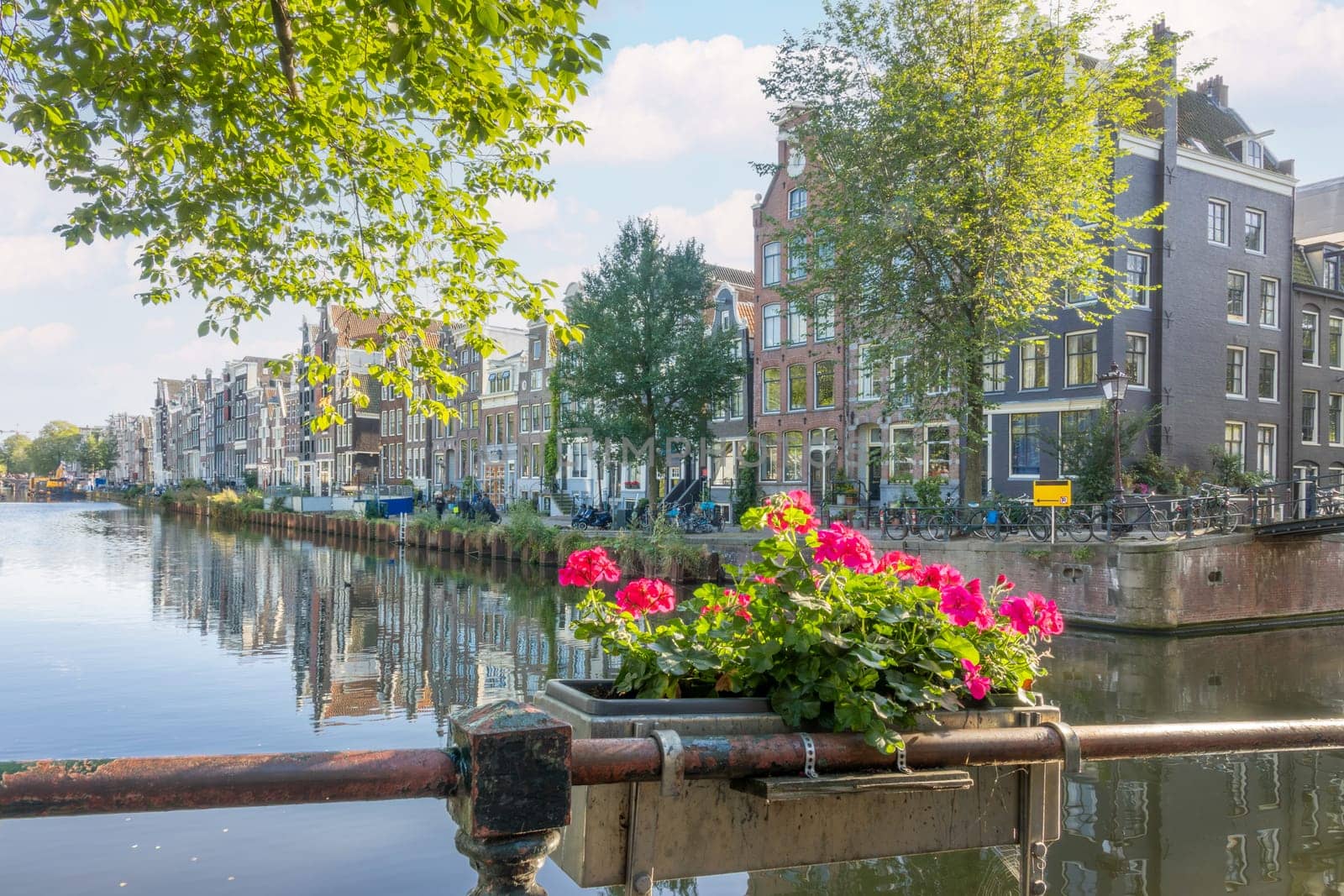 Netherlands. Sunny day on the Amsterdam canal. Typical Dutch buildings on the waterfront. Bright flowers in the foreground
