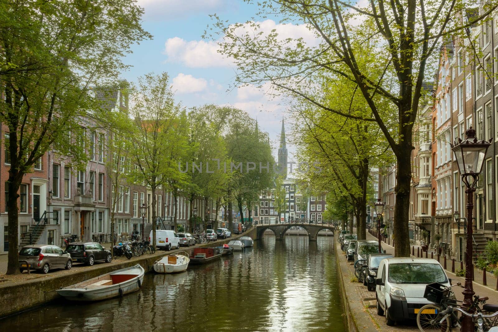 Netherlands. Summer day on a canal in the center of Amsterdam. Lots of boats and cars parked on the embankments