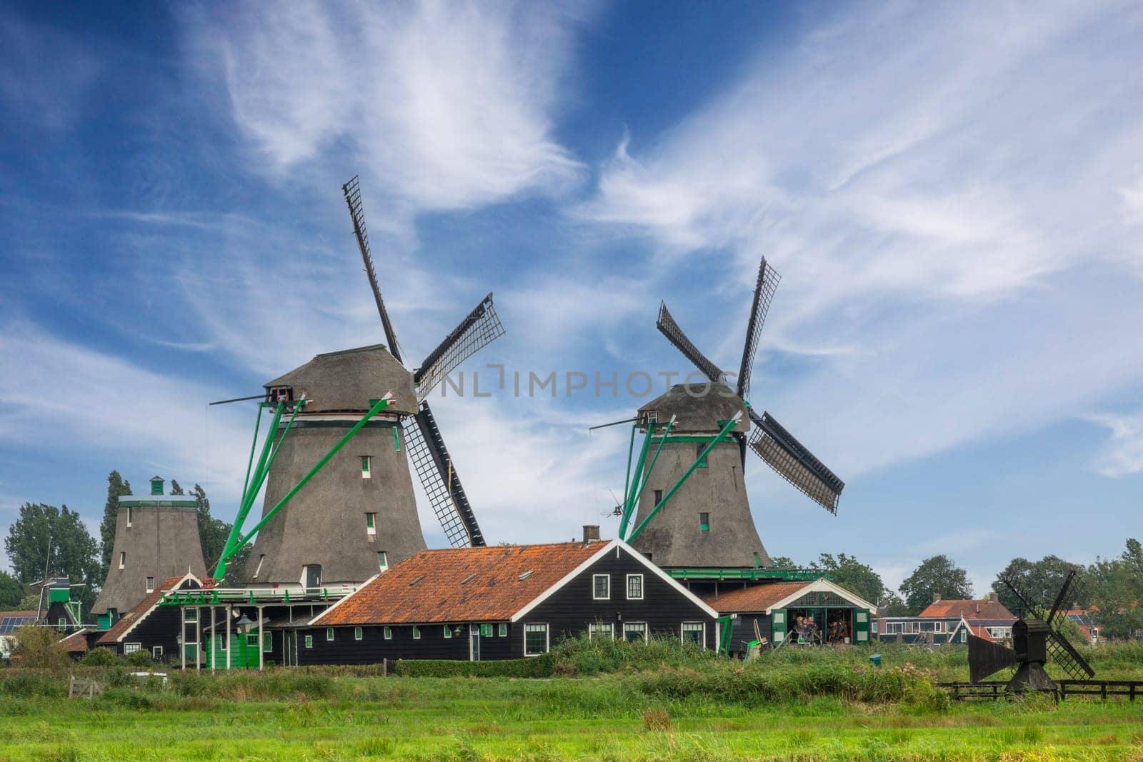 Netherlands. Summer day in Zaanse Schans. Two old windmills and high clouds in the blue sky