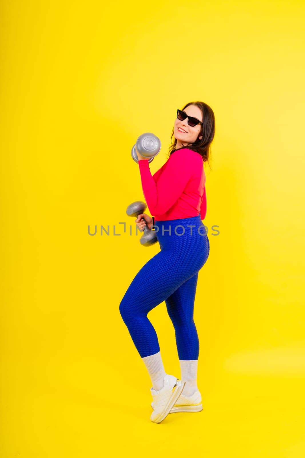 Sporty plump woman doing an exercises with dumbbells. Sports motivation and healthy lifestyle