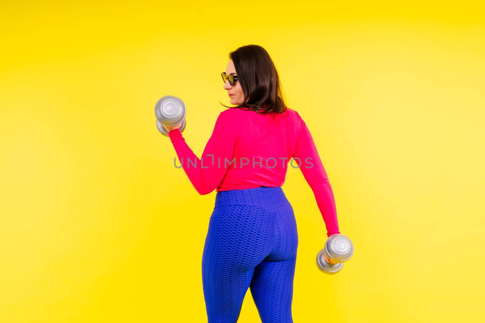 Sporty plump woman doing an exercises with dumbbells. Sports motivation and healthy lifestyle