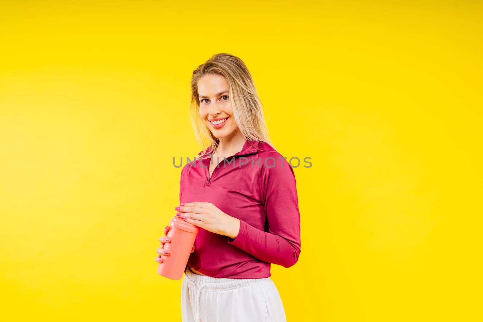 Studio fitness female portrait with bottle of water isolated on yellow background by Zelenin