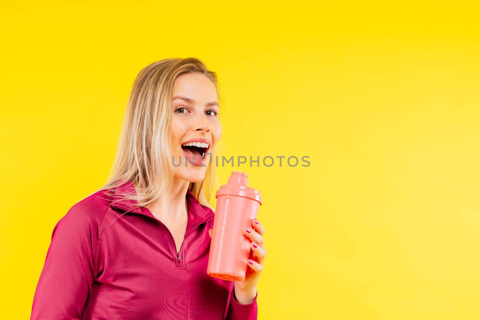 Studio fitness female portrait with bottle of water isolated on yellow background by Zelenin